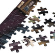 Close-up of Gothic Angel Music Room Jigsaw Puzzle in Tin pieces on a white surface.