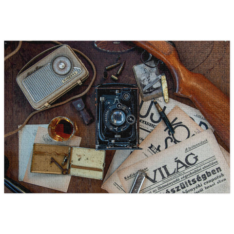 Vintage Explorer Desk Puzzle Tin Edition featuring old camera, radio, documents, and personal items on a textured vintage desk.